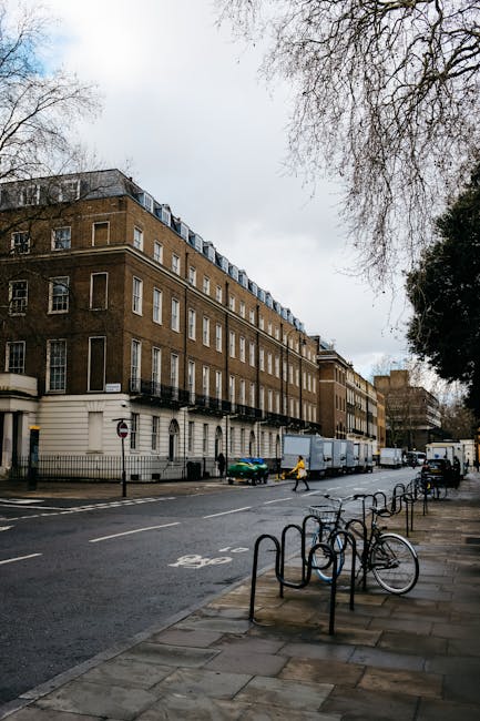 A wide view of a multi-storey brown brick building on Stroud Green Road in Finsbury Park, with several windows and balconies along the facade, under an overcast sky. In front of the building, beneath
